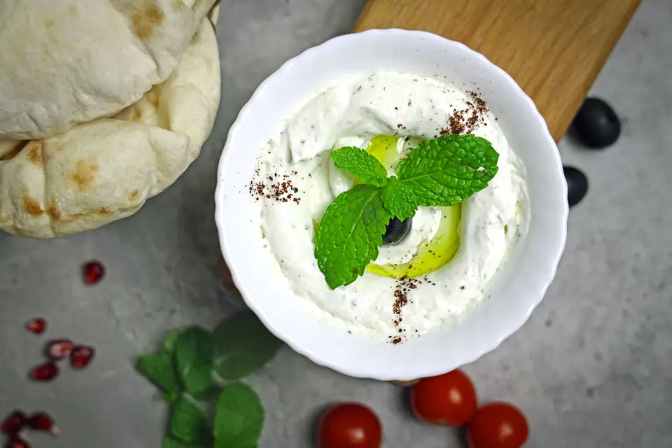 A bowl of yogurt with olives and mint leaves